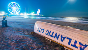 Boat on the beach in Atlantic City with the boardwalk and lights in the background at dusk